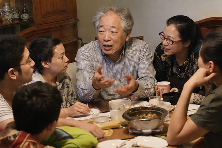 A family in animated conversation around a shared meal